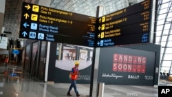 Seorang pekerja berjalan di bawah rambu petunjuk arah di ruang tunggu keberangkatan internasional di Terminal 3 Bandara Internasional Soekarno-Hatta di Banten, 28 April 2017. (Foto: AP)