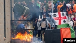 Protestors throw a garbage bin on fire outside a hotel in Rotherham, Britain, Aug. 4, 2024.