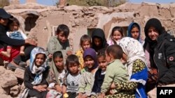 Anak-anak Afghanistan duduk di dekat rumah mereka yang rusak setelah gempa bumi di desa Wardakha, distrik Zendeh Jan, provinsi Herat pada 10 Oktober 2023. (Mohsen KARIMI / AFP)