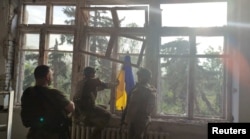 Ukrainian soldiers place a flag at a building in a location given as Blahodatne, Donetsk Region, Ukraine, in this screengrab taken from a handout video released on June 11, 2023.