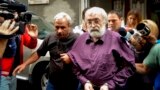 FILE — Romanian guru Gregorian Bivolaru is escorted to a vehicle after a hearing at the Romanian Police headquarters in Bucharest, Romania, Aug. 24, 2016. 