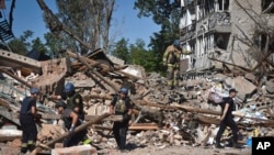 Ukrainian emergency services members work next to buildings destroyed in Russian strikes in the town of Orikhiv, Zaporizhzhia region, Ukraine, July 10, 2023.