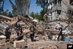 Ukrainian emergency services members work next to buildings destroyed in Russian strikes in the town of Orikhiv, Zaporizhzhia region, Ukraine, July 10, 2023.