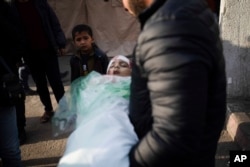 A relative of Masa Shouman holds her body during her funeral in Rafah, southern Gaza, Jan. 17, 2024.
