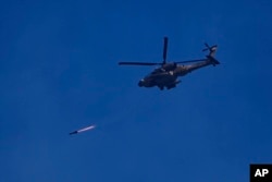 An Israeli Apache helicopter fires a missile in direction of the Gaza Strip, as seen from southern Israel, Dec. 6, 2023.