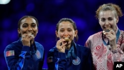 Fencing gold medalist Lee Kiefer, center, of the US celebrates with silver medalist Lauren Scruggs, left, of the US and bronze medalist Eleanor Harvey of Canada during the 2024 Summer Olympics, July 28, 2024, in Paris.