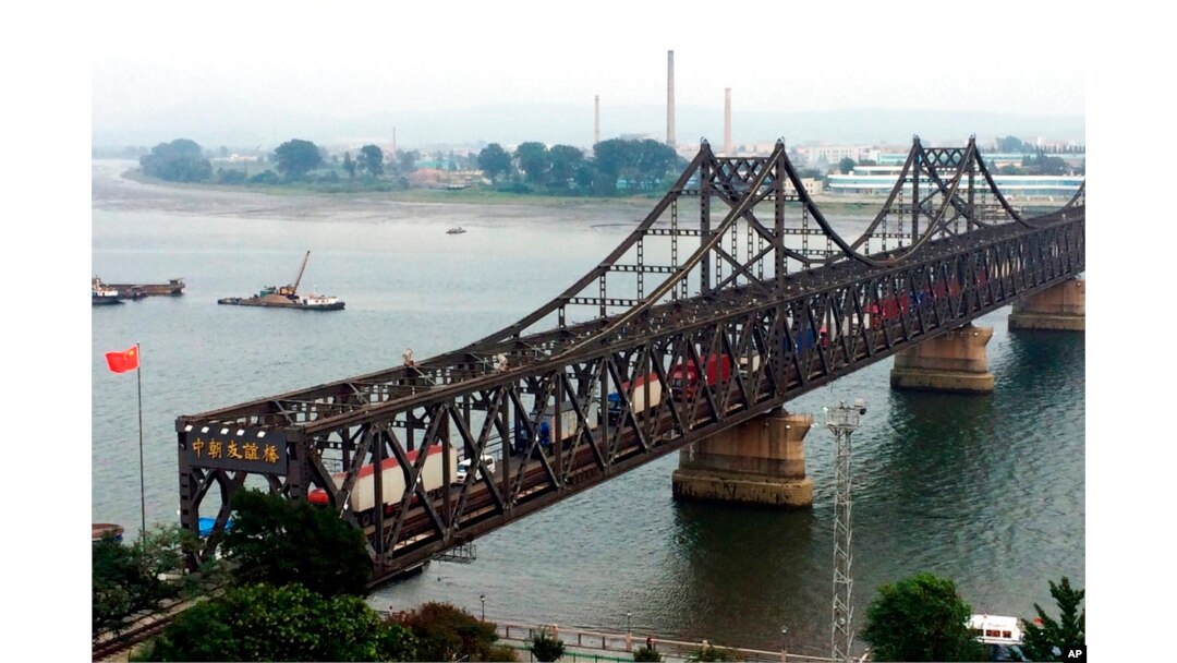 FILE - Trucks cross the bridge connecting Dandong, China, and Sinuiju, North Korea, Sept. 4, 2017. North Korea fears that planned Chinese telecom facilities, including some near Dandong, could cause "serious interference."