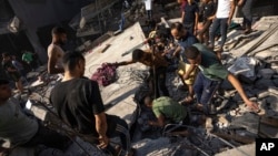 Palestinians search for bodies and survivors in the rubble of a residential building leveled in an Israeli airstrike, in Al Shati refugee camp Oct. 12, 2023.
