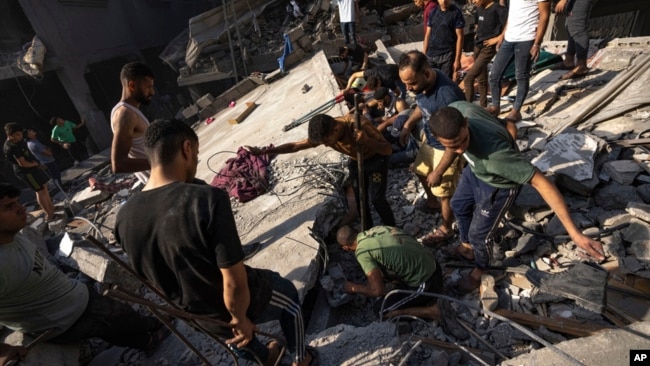 Palestinians search for bodies and survivors in the rubble of a residential building leveled in an Israeli airstrike, in Al Shati refugee camp Oct. 12, 2023.