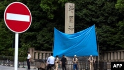 日本东京靖国神社入口处的石柱遭涂鸦，当局用一块蓝布遮挡。（2024年8月19日）