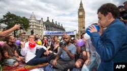 Para pengunjuk rasa menghirup dinitrogen oksida, yang dikenal sebagai gas tawa, di luar Gedung Parlemen di pusat kota London, 1 Agustus 2015. (AFP PHOTO/JACK TAYLOR)