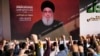 Supporters of the Iranian-backed Hezbollah group raise their fists and cheer as Hezbollah leader Hassan Nasrallah appears via a video link during a rally in Beirut, Lebanon, Nov. 3, 2023. 