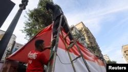 On the first day of voting, Dec. 9, 2023, workers in Cairo place an Egyptian flag at the entrance of one of the schools that will be used as a polling station in Egypt's presidential elections.