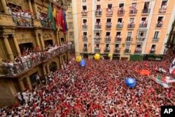 Orang-orang berpakaian merah dan putih memenuhi alun-alun balai kota menjelang peluncuran roket 'Chupinazo', menandai dimulainya pesta San Fermín 2023 di Pamplona, Spanyol, Kamis, 6 Juli 2023. (AP/Alvaro Barrientos)