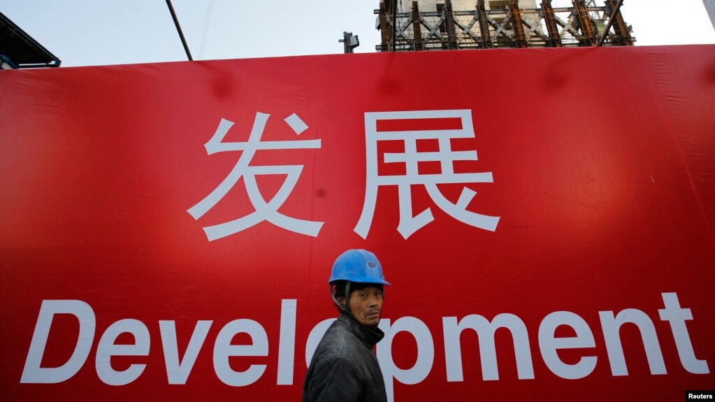 资料照:一名工人走过北京一处建筑工地的宣传标语。(2014年12月12日)