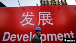 资料照：一名工人走过北京一处建筑工地的宣传标语。（2014年12月12日）