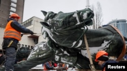 Municipal workers take down a monument to Mykola Schors, a Soviet field commander during the Russian Civil War, in Kyiv, Ukraine, Dec. 9, 2023.