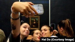 FILE - Visitors take pictures of themselves with the famous Leonardo Da Vinci's Mona Lisa at the Louvre in Paris, France on Sept. 11, 2022. (Photo by Hai Do)