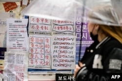 FILE - A student glances at anti-Chinese government posters displayed outside a university in Seoul on Nov. 28, 2022, following protests over China's zero-COVID policy.