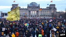ພວກທີ່ເຂົ້າຮ່ວມໃນການເດີນຂະບວນປະທ້ວງຕໍ່ຕ້ານ ການຈຳແນກເຊື້ອຊາດ ແລະ ກຸ່ມການເມືອງຝ່າຍຂວາ ໄດ້ເຕົ້າໂຮມກັນຢູ່ຕໍ່ໜ໊າຕຶກລັດຖະສະພາ ໄຣສຕາກ (Reichstag) ໃນນະຄອນຫຼວງເບີລິນ ຂອງເຢຍຣະມັນ, ວັນທີ 21 ມັງກອນ 2024. 