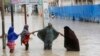 ILUSTRASI - Perempuan berjalan melewati air banjir setelah hujan lebat, di Mogadishu Somalia, Senin, 20 November 2023. (AP/Farah Abdi Warsame)