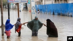 ILUSTRASI - Perempuan berjalan melewati air banjir setelah hujan lebat, di Mogadishu Somalia, Senin, 20 November 2023. (AP/Farah Abdi Warsame)