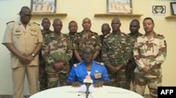 This video frame grab image obtained by AFP from ORTN - Télé Sahel on July 26, 2023, shows Colonel Major Amadou Abdramane (C), spokesperson for the National Committee for the Salvation of the People (CNSP), speaking during a televised statement in Niger.