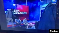 Workers lie on the floor as armed people take over a TV studio at Ecuador's TV station TC during a live broadcast, in this still image of a Reuters' recording of the event in Guayaquil, Ecuador, Jan. 9, 2024. (Reuters TV/via Reuters Ecador)