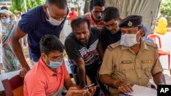 Relatives of victims of Friday's train accident try to identify loved ones by looking at photographs on the phone of an official at a hospital in Bhubaneswar in the eastern state of Odisha, India, June 5, 2023.