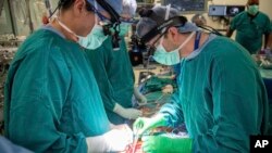 FILE - In this photo provided by Duke Health, surgeons Dr. Jacob Schroder, left, and Dr. Zachary Fitch perform a heart transplant at Duke University Hospital in Durham, NC, in October 2022.