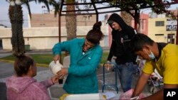 Migrantes venezolanos toman café en un parque en Tacna, Perú, el 29 de abril de 2023. 