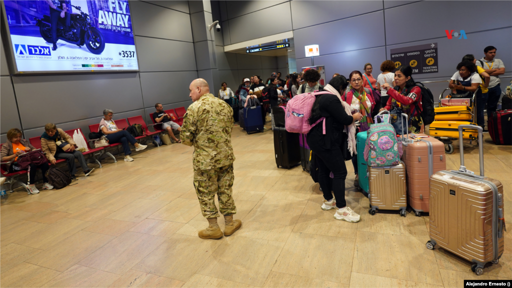 Un militar observa a los turistas y ciudadanos extranjeros, la mayoría latinoamericanos, mientras esperan regresar a sus países en vuelos repatriación desde un Israel en guerra, en el aeropuerto de Telaviv, el 13 de octubre de 2023.