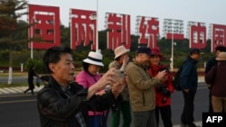 中国福建厦门竖立起一个台湾金门岛可以看到的“一国两制统一中国”的大型标语牌，旅游者在前拍照。（2024年1月12日）