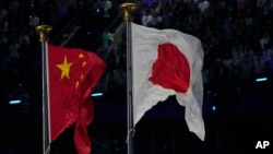 FILE - Chinese and Japanese flags fly at the Asian Games in Hangzhou, China, Oct. 8, 2023. Chinese nationals are now the largest group of immigrants in Japan.