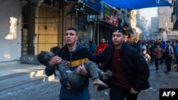 以色列2023年12月1日恢复对加沙地带南部拉法的轰炸后，一名巴勒斯坦男子抱着一名受伤的男孩。