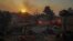 A man on a motorcycle looks on as a shipyard which is on fire in Mandra west of Athens, on Tuesday, July 18, 2023. In Greece, where a second heatwave is expected to hit Thursday, three large wildfires burned outside Athens for a second day. 