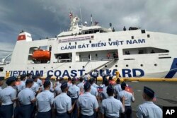 Personel Penjaga Pantai Filipina melambaikan bendera Vietnam dan Filipina untuk menyambut kedatangan kapal Penjaga Pantai Vietnam (VCG), CSB 8002, di Manila, Filipina, Senin, Agustus 2024. (Joeal Calupitan/AP)