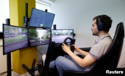 Seorang operator mengendalikan mobil tanpa pengemudi Fetch dari kantor Imperium Drive di Milton Keynes, Inggris, 8 Juni 2022. (REUTERS/Andrew Boyers)