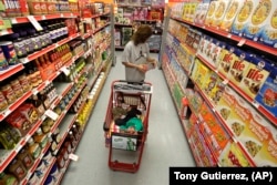 FILE - A woman looks at products in the aisle of a store as her daughter naps in a shopping cart in Waco, Texas on Dec. 14, 2010. (AP Photo/Tony Gutierrez, File)