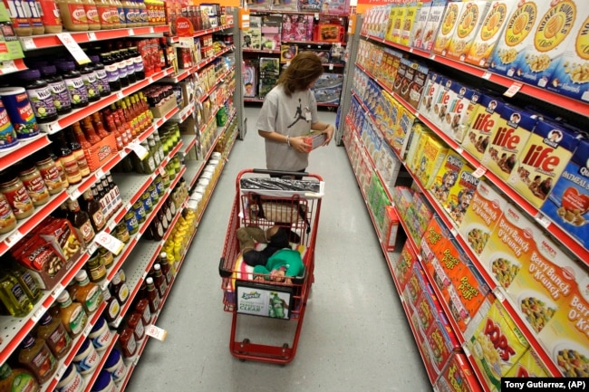 FILE - A woman looks at products in the aisle of a store as her daughter naps in a shopping cart in Waco, Texas on Dec. 14, 2010. (AP Photo/Tony Gutierrez, File)