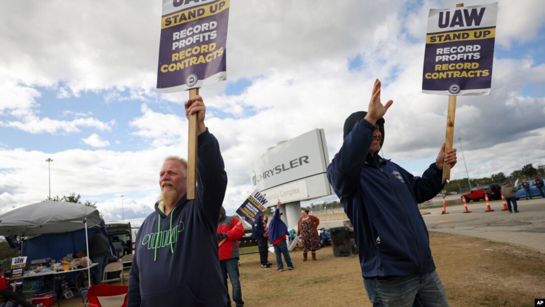 FILE - Striking United Auto Workers members Rob Marchese, left, and Neil Peters picket at the Stellantis Toledo Assembly Complex on Oct. 7, 2023, in Toledo, Ohio.