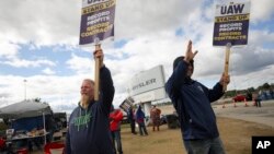 FILE - Striking United Auto Workers members Rob Marchese, left, and Neil Peters picket at the Stellantis Toledo Assembly Complex on Oct. 7, 2023, in Toledo, Ohio.