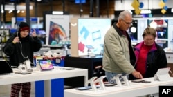 Bob Adkison and his wife, Rosie, look at tablet computers at a Best Buy, Nov. 24, 2023, in Charlotte, N.C. With many consumers squeezed by inflation and high interest rates, U.S. holiday spending was expected to rise at its slowest pace in five years.