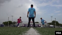 Kevin Chin melatih dua anak didiknya di lapangan sepak bola di Kota Pembroke Pines (VOA Indonesia)