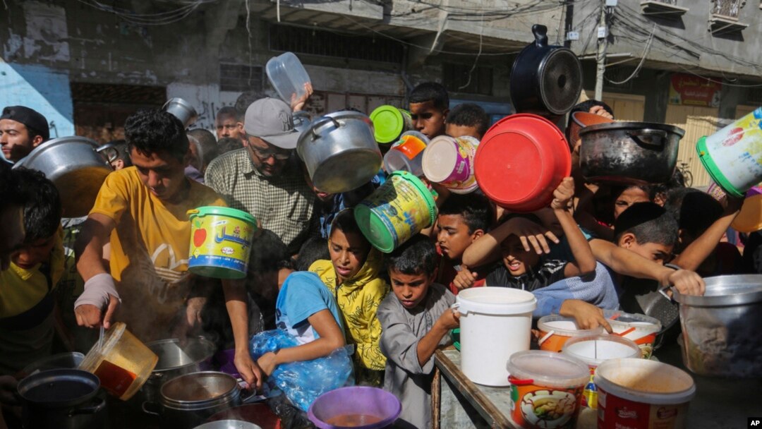 Palestinos, entre ellos niños, se amontonan unos sobre otros mientras esperan la distribución de alimentos en Rafah, sur de la Franja de Gaza, el 8 de noviembre de 2023.