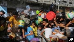 Palestinos, entre ellos niños, se amontonan unos sobre otros mientras esperan la distribución de alimentos en Rafah, sur de la Franja de Gaza, el 8 de noviembre de 2023.