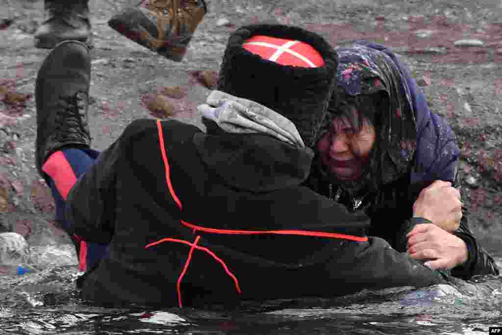 A cossack helps a woman get out of the Kara-Balta river during the celebration of the Epiphany holiday near the village of Sosnovka, some 90 kms from Bishkek, Kyrgyzstan.&nbsp;Among Orthodox Christians, the feast of Epiphany celebrates the day the spirit of God descended upon believers in the shape of a dove during Jesus Christ&#39;s baptism in the river Jordan.&nbsp;