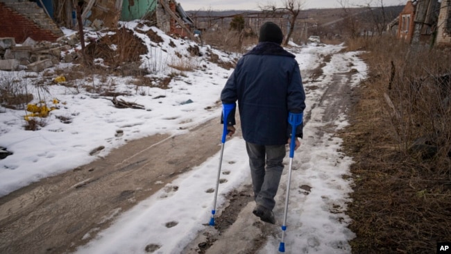 Andrii Cherednichenko, camina por un sendero nevado en Kamyanka, Ucrania, el domingo 19 de febrero de 2023. En esta ciudad marcada por la guerra en el noreste de Ucrania, los residentes examinan cada paso en busca de minas terrestres. (Foto AP/Vadim Ghirda)