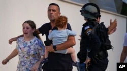 FILE - Israeli police officers evacuate a family from a site hit by a rocket fired from the Gaza Strip, in Ashkelon, Israel, on Oct. 7, 2023.