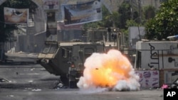 Bom yang dilempar oleh seorang warga Palestina meledak di dekat kendaraan militer Israel dalam penyerbuan militer di kamp pengungsi Jenin, Tepi Barat, pada 4 Juli 2023. (Foto: AP/Majdi Mohammed)